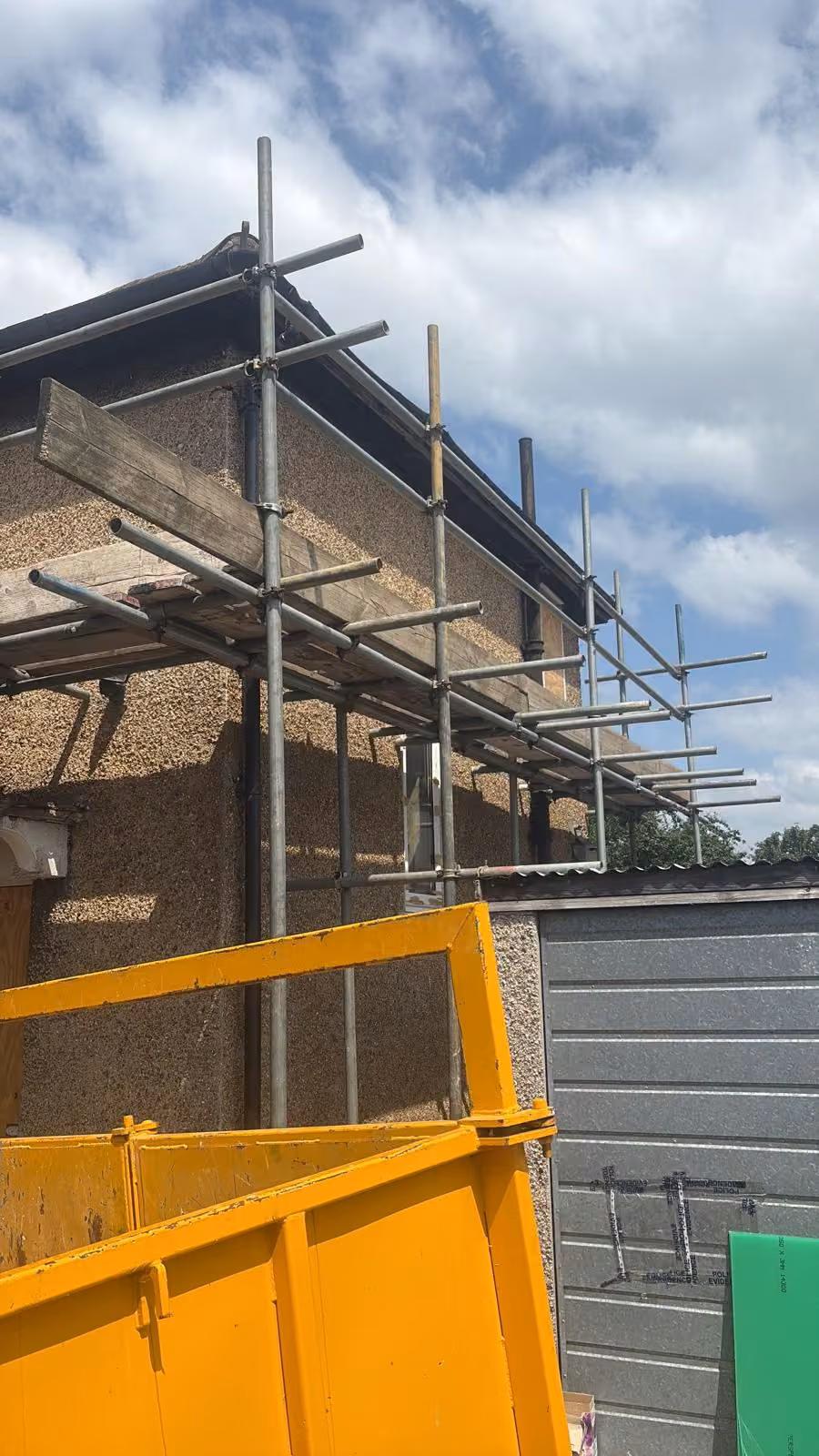 Scaffold around a rear extension with a skip in the garden